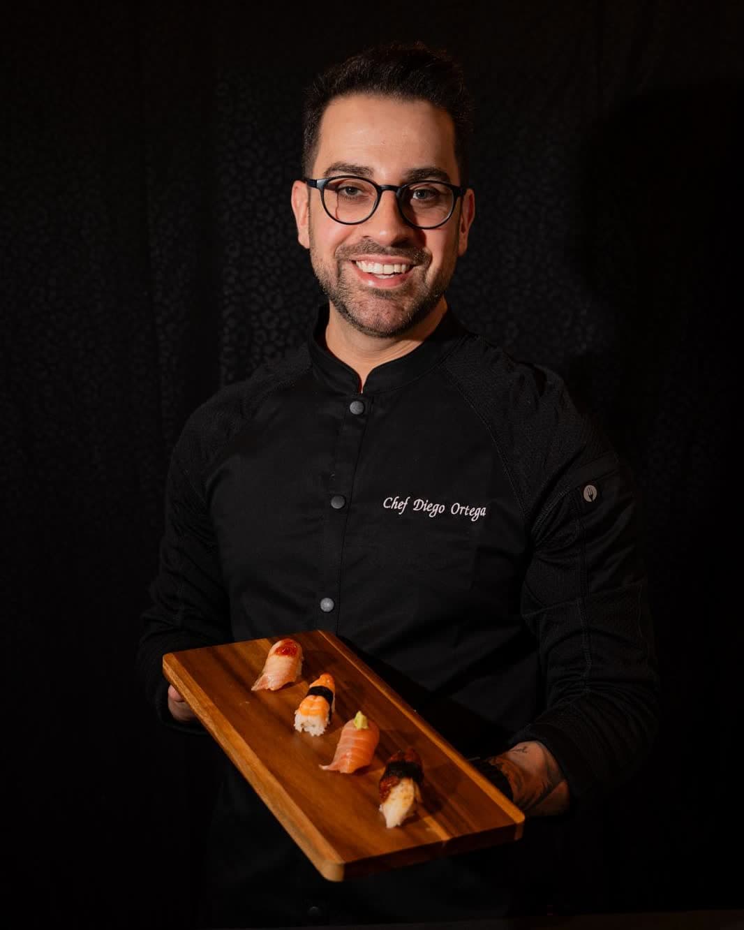 Chef Diego Ortega holding a board of fresh nigiri, founder of Nukazi Sushi